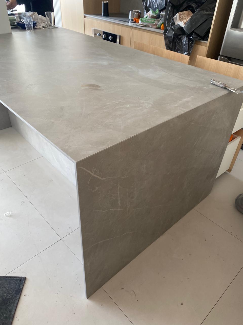 Ilha de cozinha em Lâmina Pupis Gray cinza com veios suaves, fechamento lateral e frontal em cascata executado pela Mister Marmoraria em São Paulo